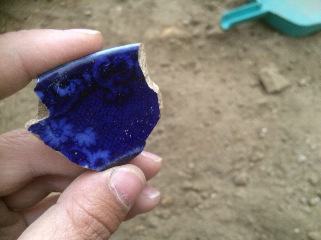 San Ignacio Archaeological Project member holding a blue glazed ceramic fragment